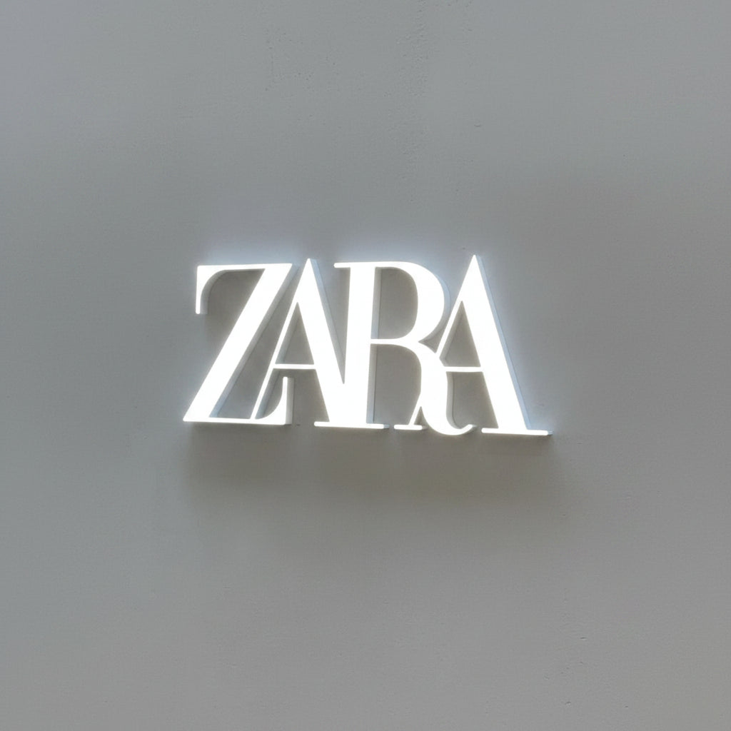 Custom Zara-style LED acrylic logo sign with bright white illumination mounted on a modern gray wall.