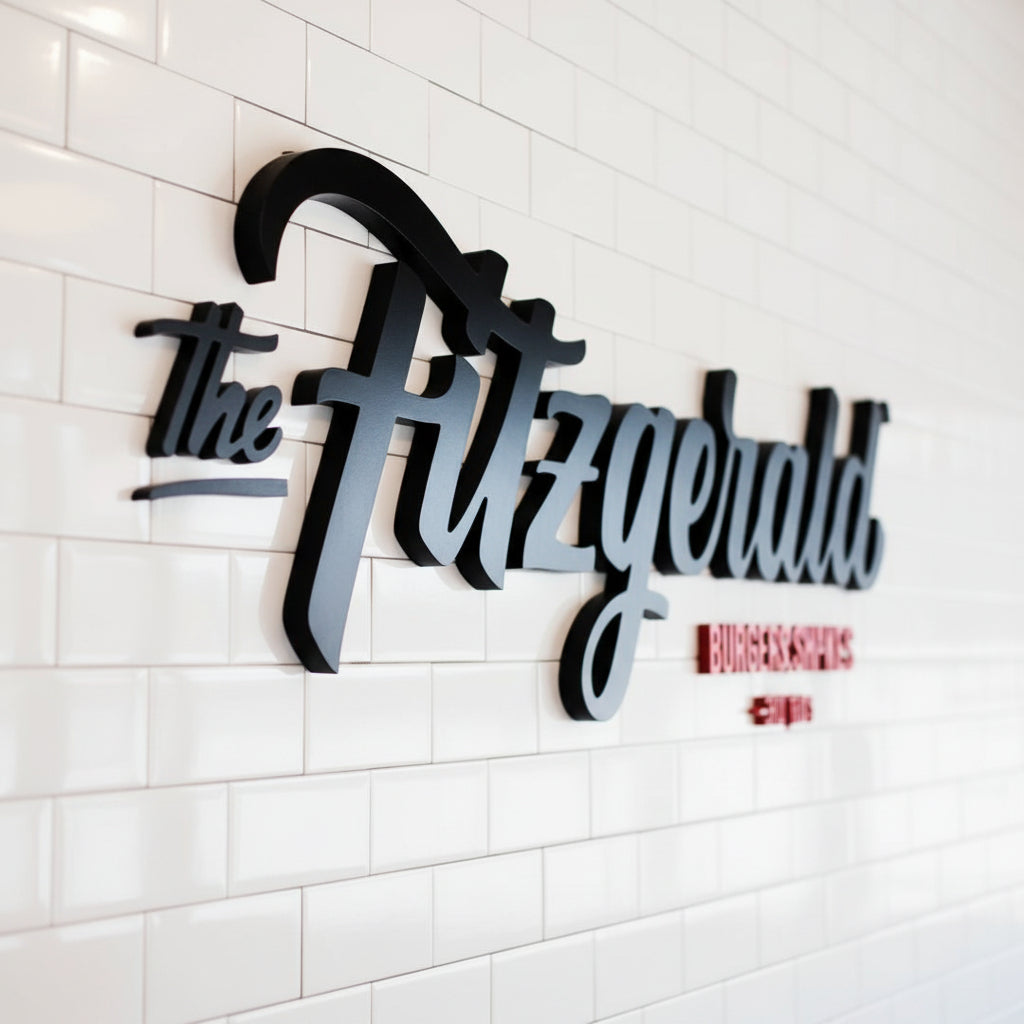 Custom black acrylic logo sign mounted on a white tiled wall, creating a bold and professional branding display for a restaurant interior.