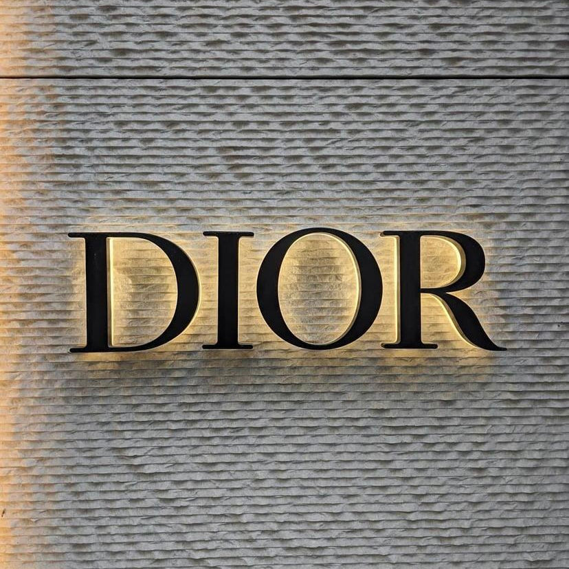 Luxury Dior logo wall art canvas featuring an illuminated fashion-inspired design on a textured gray wall.