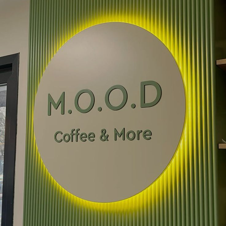 Modern café branding sign featuring illuminated circular logo display for coffee shop interior