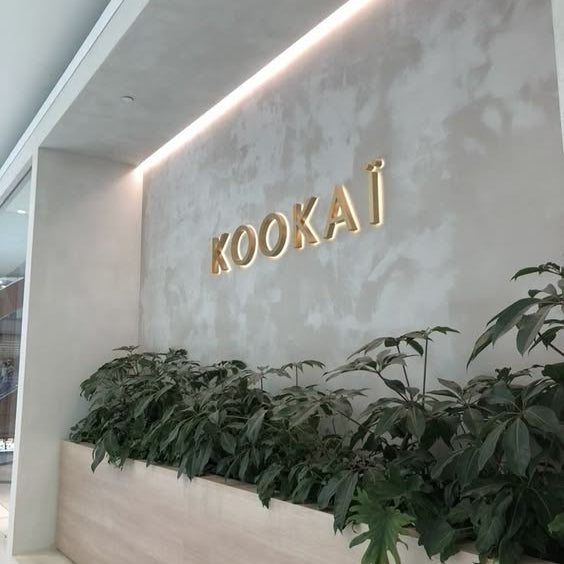 Premium gold acrylic letter wall sign mounted on a textured feature wall in a modern commercial office interior.