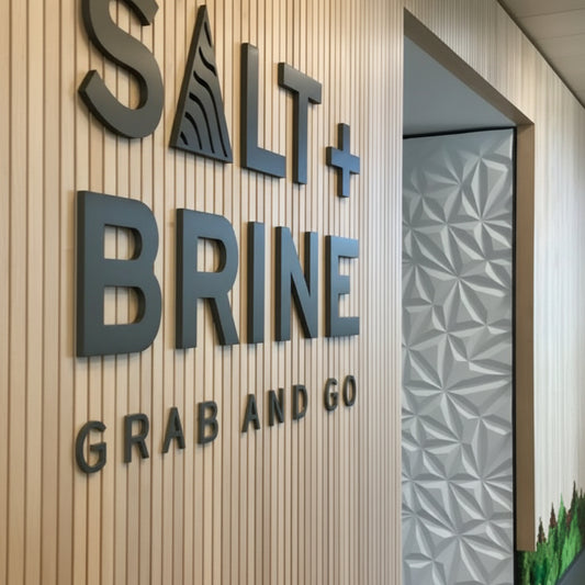 Custom 3D acrylic letter logo sign mounted on a wooden slat wall, ideal for office reception, retail stores, cafés, and corporate business branding.