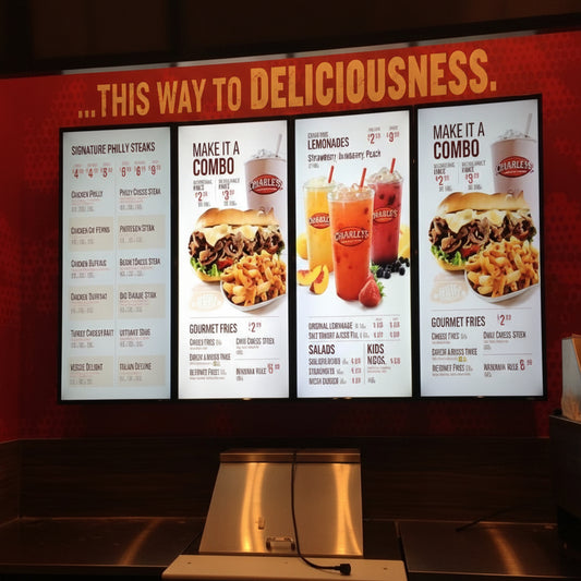 Modern backlit menu display installed above a fast-food ordering counter with bright LED graphics