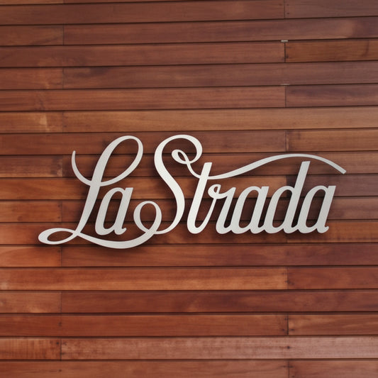 Custom LaStrada script metal wall sign mounted on a wooden slat wall, ideal for restaurants, cafés, offices, and business branding.