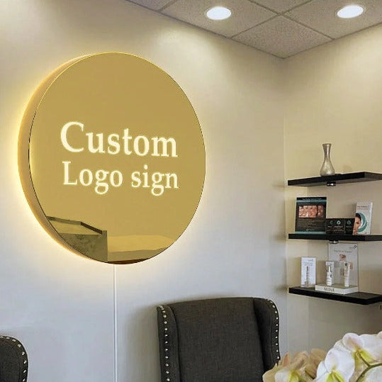 Custom round LED acrylic logo sign with elegant halo backlighting mounted on an office wall for professional business branding.