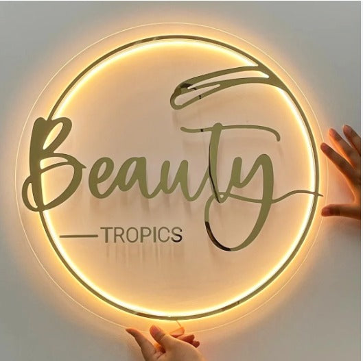 Custom round acrylic beauty logo sign with warm halo LED backlighting, perfect for salons, spas, and beauty studios.