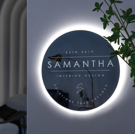 Custom round acrylic logo sign with elegant white halo LED backlighting mounted on a modern office wall.