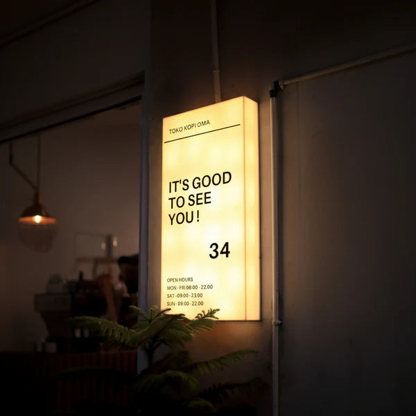 Modern wall-mounted acrylic LED business sign displaying custom welcome message and storefront information.