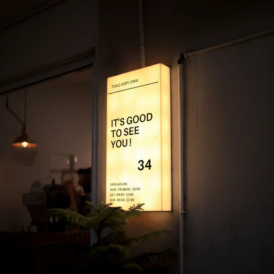 Modern wall-mounted acrylic LED business sign displaying custom welcome message and storefront information.
