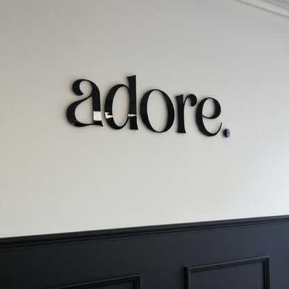 Gloss black acrylic letter sign mounted on a white wall, creating a sleek and professional business branding display.