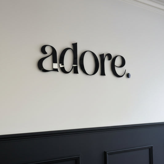 Gloss black acrylic letter sign mounted on a white wall, creating a sleek and professional business branding display.