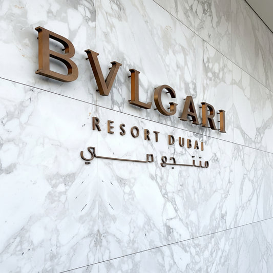 Premium bronze acrylic letter sign mounted on a marble wall, creating an elegant hotel reception and luxury business branding display.