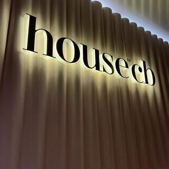 Premium custom halo-lit metal letter sign with warm white LED backlighting mounted on a decorative fluted wall for elegant business branding.