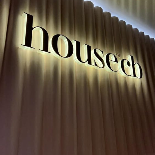 Premium custom halo-lit metal letter sign with warm white LED backlighting mounted on a decorative fluted wall for elegant business branding.