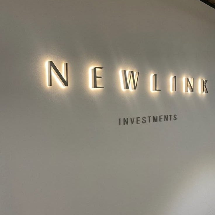 Premium custom halo-lit metal logo sign with warm white LED backlighting mounted on an office wall, ideal for corporate branding and reception signage.
