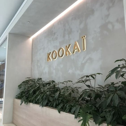 Premium gold acrylic letter wall sign mounted on a textured feature wall in a modern commercial office interior.