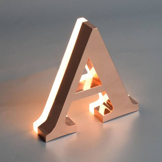 Rose gold stainless steel letter sign with halo LED backlighting creating a luxury floating effect